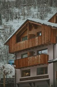 a house with a wooden balcony in the snow at Residence & Wellness 3MILA in Peio Fonti
