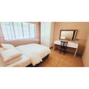 a bedroom with a bed and a desk with a mirror at Gorgeous Garden Villa 3 in Gillitts-Emberton
