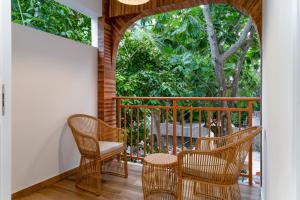 a balcony with three chairs and an archway at Rivethi Veyli Ukulhas in Ukulhas