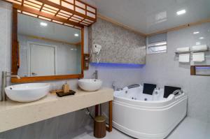 a bathroom with two sinks and a tub and a mirror at Rivethi Veyli Ukulhas in Ukulhas