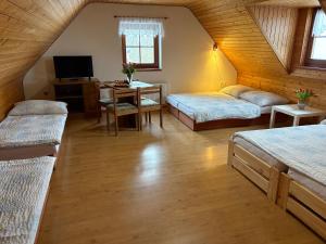 a attic room with two beds and a desk with a television at Penzion Hamštejn in Koberovy