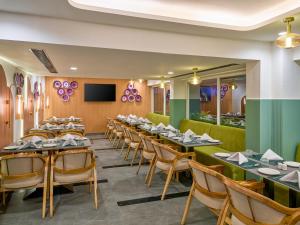a dining room with tables and chairs and a flat screen tv at Regenta Z Vadodara in Vadodara