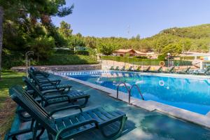 a swimming pool with lounge chairs next to a swimming pool at Camping-Bungalows Altomira in Navajas