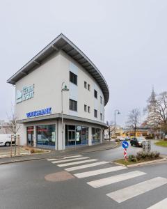 a large white building with a crosswalk in the street at Das schlaf&GUT - Self Check-In in Leibnitz