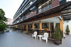 - une terrasse avec 2 chaises blanches et un bâtiment dans l'établissement TH beach hotel, à Hua Hin