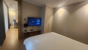 a bedroom with a bed and a flat screen tv at Haeon stay haeundae in Ch'ŏngsap'o
