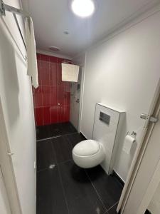 a bathroom with a toilet and a red wall at Entire Studio in Moonee Ponds with Free Parking in Melbourne +19 photos