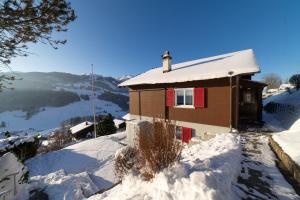 a house with a red door is covered in snow at Studio Muerner in Wildhaus