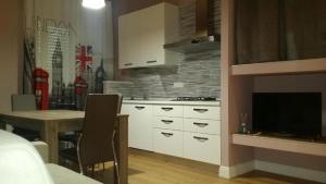 a kitchen with white cabinets and a table and a television at Affitti brevi Liguria - La Conchiglia in Savona