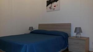 a bedroom with a bed with a blue bedspread and a night stand at Affitti brevi Liguria - La Conchiglia in Savona