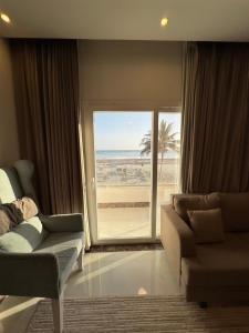 a living room with a couch and a view of the beach at Taqah Beach Front Apartment in Ţāqah
