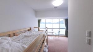 a bedroom with a bed and a table and a window at 森口屋アートスクエア in Shodoshima
