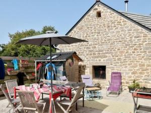 a patio with a table and chairs and an umbrella at L'écurie Kerdoel in Cléder