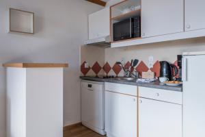a kitchen with white cabinets and a microwave at Résidence Pierre & Vacances La Rivière in Chamonix
