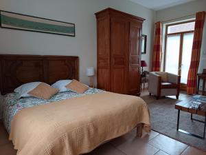 a bedroom with a large bed and a chair at LE JARDIN DU ROSSIGNOL in Willeman