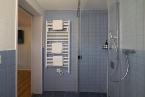 a blue tiled bathroom with a shower and towels at Studio Muerner in Wildhaus