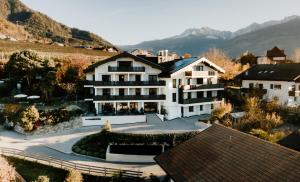 a large white building with mountains in the background at Stricker Aparthotel in Tirolo