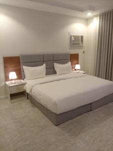 a bedroom with a large white bed with two lamps at غيمة in Hail