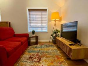 a living room with a red couch and a flat screen tv at 1BR Haven in Crewe - Modern, Chic & Central in Crewe