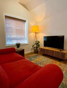 a living room with a red couch and a flat screen tv at 1BR Haven in Crewe - Modern, Chic & Central in Crewe