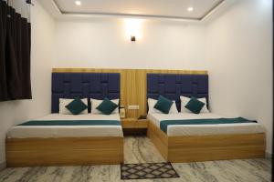 a bedroom with two beds with blue headboards at HOTEL chandra garden in Govardhan