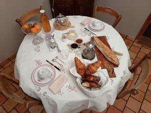 a table with a white table cloth with bread and toast at LE JARDIN DU ROSSIGNOL in Willeman