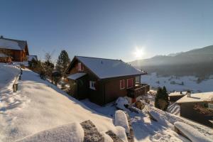 a house in the snow with the sun in the background at Studio Muerner in Wildhaus +8 photos