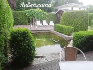 a backyard with a pond with two chairs and a pond at Ferienwohnungen Margaretenhof am Plauer See in Brandenburg an der Havel