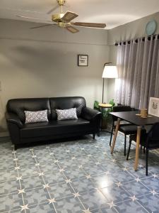 a living room with a black couch and a table at Udon House in Udon Thani