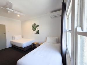 two beds in a room with a window at Plantation Hotel Coffs Harbour in Coffs Harbour