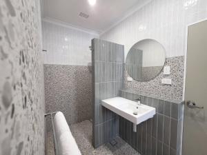 a bathroom with a sink and a mirror at Plantation Hotel Coffs Harbour in Coffs Harbour