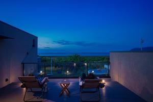 two people sitting in chairs on a balcony at night at Star Seven Itoshima in Itoshima