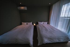 two twin beds in a room with a window at Star Seven Itoshima in Itoshima