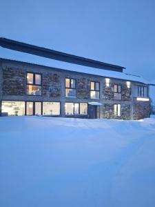 a building with snow in front of it at Hotel-restaurant Stumari in Ushguli