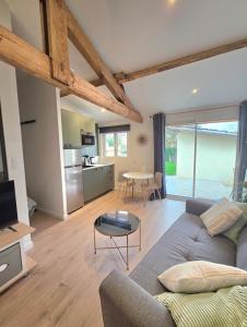 a living room with a couch and a table at Logement neuf tout équipé, climatisé, terrasse au calme, VELOS, barbecue, proche du bourg et des plages océanes, wifi, linge et ménage compris in Mimizan