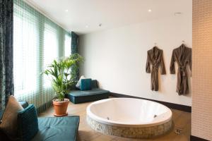 een grote badkamer met een bad, een bank en een stoel bij Manzo's Suites in Zaandam