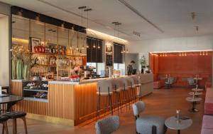 Eine Bar in einem Restaurant mit Stühlen und einer Frau an der Theke in der Unterkunft Hotel Miano by Limehome in München