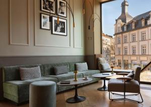 ein Wohnzimmer mit Sofa, Tischen und einem Fenster in der Unterkunft Hotel Miano by Limehome in München