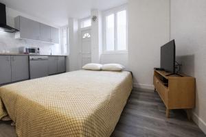 a bedroom with a bed and a flat screen tv at Le Trilou - By BEST KEYS - Triplex Totalement Climatisé 3 Chambres - Lit King Size - Smart TV Canal Plus & Amazon Prime - Cuisine Équipée - Télétravail - Proche Centre & Canal de Bourgogne - Check-in Autonome in Brienon-sur-Armançon