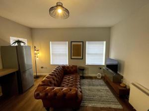 a living room with a leather couch and a television at Central Industrial Chic 2-Bedroom Flat in Crewe