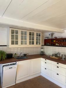 a kitchen with white cabinets and wooden counter tops at Guest house Æbelnæs, Møn in Stege +13 photos