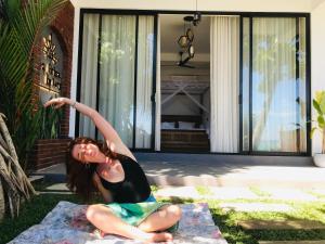 a woman sitting on the grass in front of a house at La Brisa By Harry Beach Villa in Dickwella
