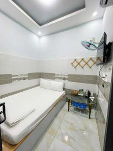 a white room with a bed and a table at Ong 5 Homestay Can Tho in Can Tho