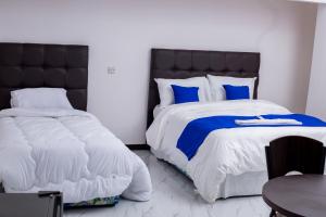 a bedroom with two beds with blue and white sheets at Salama Blue Lodge in Lusaka