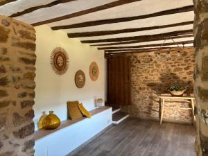 a room with a stone wall and wooden ceiling at masia riu dels arbres in Benasal +15 photos