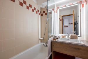 a bathroom with a sink and a tub and a mirror at Résidence Pierre & Vacances Les Temples du Soleil in Val Thorens