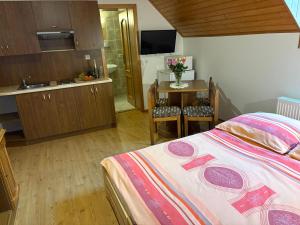 a bedroom with a bed and a kitchen with a table at Penzion Hamštejn in Koberovy