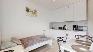 a kitchen with white cabinets and a table and chairs at Apartament Fibra Bounty in Rybnik