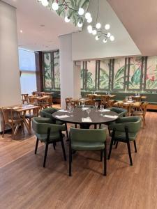 a restaurant with wooden tables and green chairs at Luix Londrina Flat 707, QS 43 m2 , ar quente e frio, c garagem in Londrina