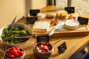 a table with cheese and vegetables on a cutting board at Château Saint Gilles - Bayeux in Guéron